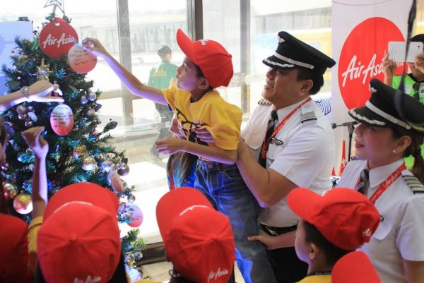 Captain Dexter Commendador helps a young boy place his message in a Christmas tree during the launching of AirAsia’s newest flight from Cebu to Davao