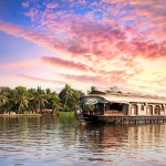 House boat in backwaters near palms at dramatic sunset sky in Alappuzha Kerala India