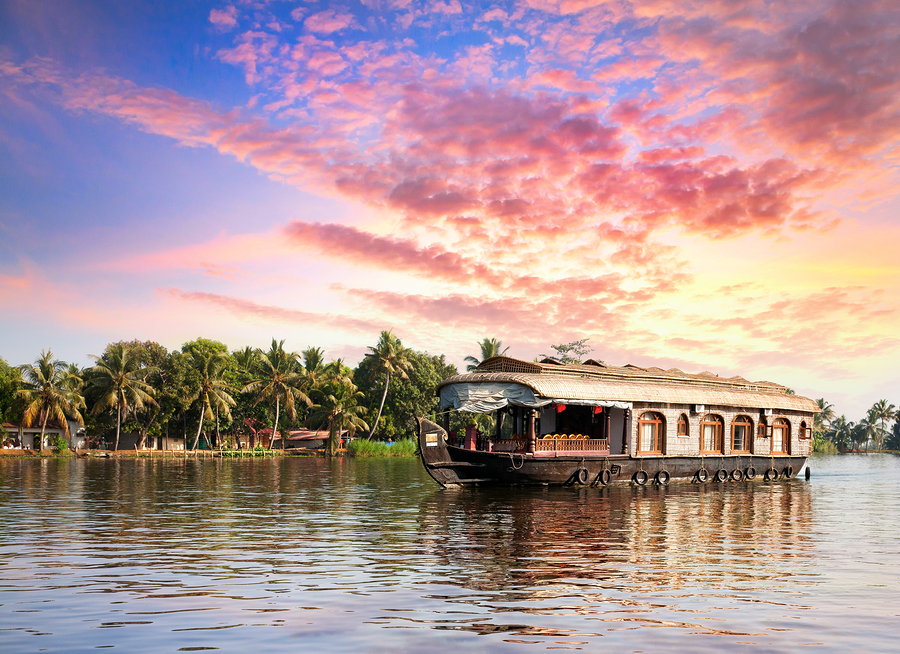 House boat in backwaters near palms at dramatic sunset sky in Alappuzha Kerala India