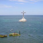 Small boats cruising towards the landmark cross above the Sunken Cemetery for a closer look