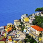 The road passes right above Riomaggiore with its mostly yellow pastel houses that lead all the way down to the narrow harbor where you'll find multi-colored boats bobbing up and down on the azure waters.