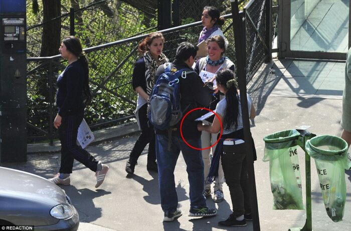 A Roma woman asks this man to sign a petition while an accomplice picks photo by Daily Mail