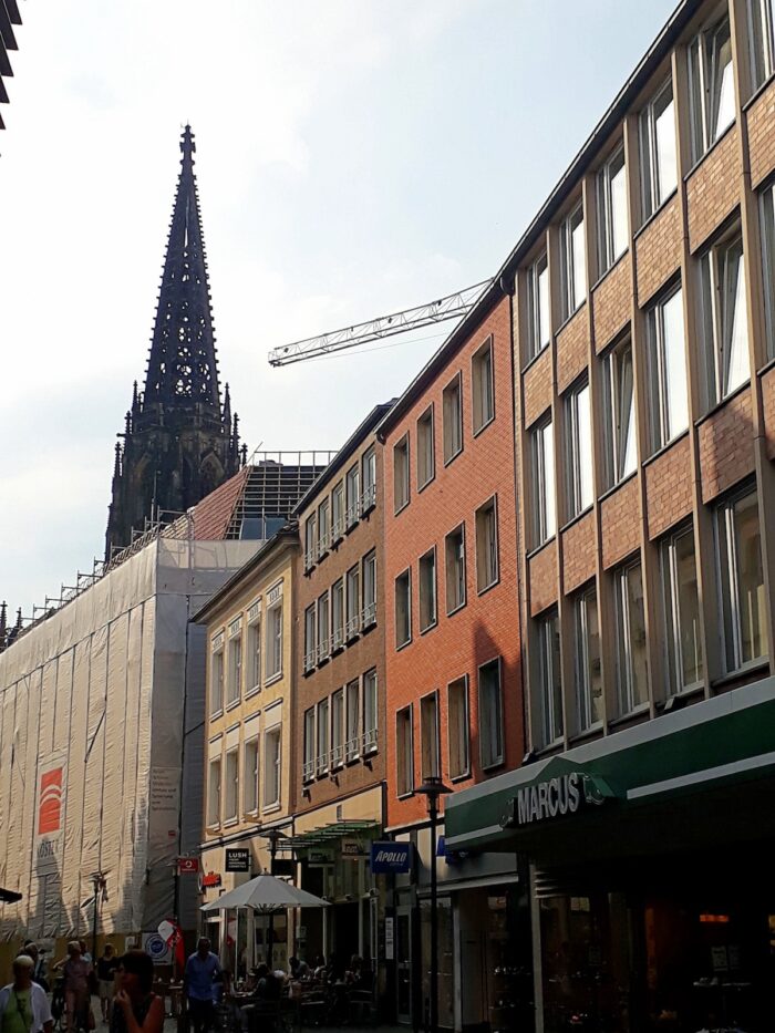 A row of shops and a looming St Lambert's