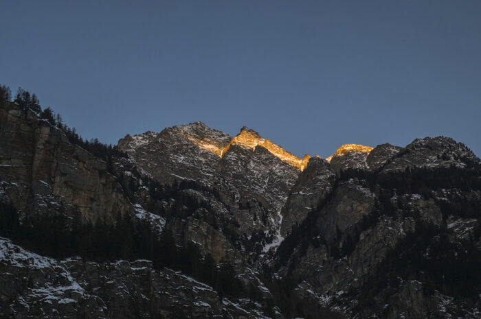 A golden shaft of sunlight illuminates the Alpine peaks.