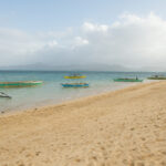 Boats dock in by the long stretch of beach. Photo by Ram Cambiado
