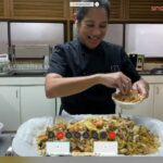 International Chef Margarita Forés, owner of such restaurants as Cibo and Grace Park, adds the finishing touches to her own version of Hokkien Mee by topping it with generous amounts of crispy fish.