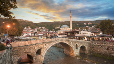Sunset view of old stone bridge and old Ottoman Sinan Pasha Mosque photo via Depositphotos