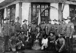 U.S. soldiers of Company C, 9th Infantry Regiment who survived a Filipino ambush in 1901 pose in Calbayog, Samar with a church bell used to signal the attack. The young boy, named Francesco, accompanied the men back to New York. The bells were taken as a war trophy to the United States.