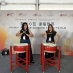 Ana Pista (right), founder and CEO of Ardent Communications, tries her hand at drumming together with a friend