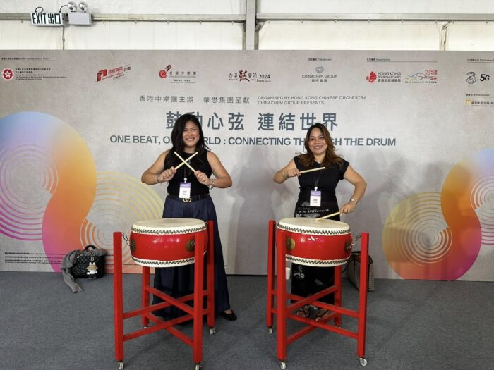 Ana Pista (right), founder and CEO of Ardent Communications, tries her hand at drumming together with a friend
