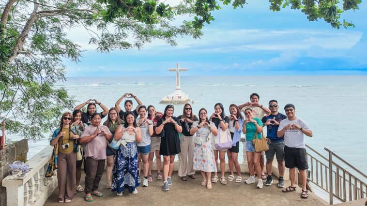 Participants pose for a photo with the Sunken Cemetery in the background