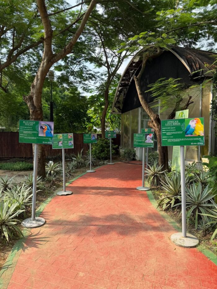"Bird information signs line the path to the aviary, where the colorful birds can be seen up close."