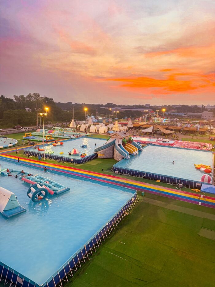 Colorful pools, playful inflatables, and exciting slides stretch across the park, offering visitors plenty of ways to cool off, have fun, and enjoy the vibrant atmosphere as the sun begins to set.