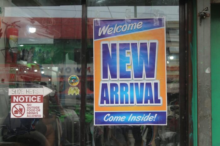 Storefront signage lures passers-by into discovering the latest pre-owned clothes and bargains.